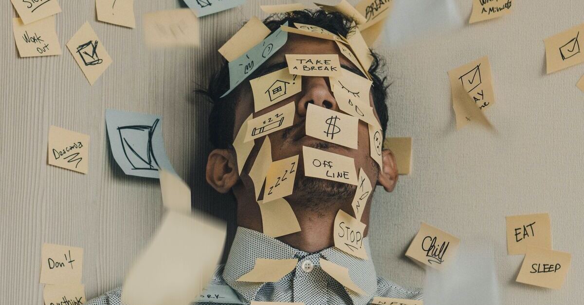 A male employee with their face and chest covered in post-it notes about bills, work and life reminders, and other responsibilities. This is to project that he is one of the examples that makes mental health in the workplace important.