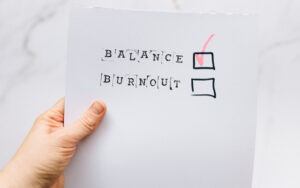 A photo of a hand holding a printout with the words “BALANCE” and “BURNOUT” beside checkboxes. There’s a big red check in the “BALANCE” checkbox.