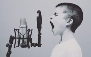 An aggressive boy shouting over the microphone to communicate his thoughts that are stressing him.